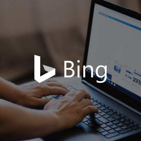 Bing logo, with person typing on laptop in background