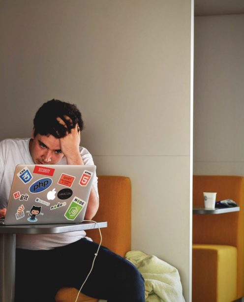 A frustrated looking man using a laptop, sitting on yellow seat