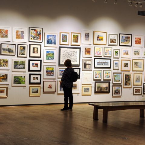 Visitors browsing the artwork at Mall Galleries